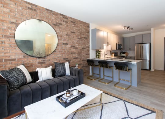 a living room with a couch and a coffee table in front of a kitchen with an island