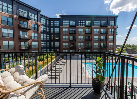 a balcony with a couch and a potted plant and a pool in the background