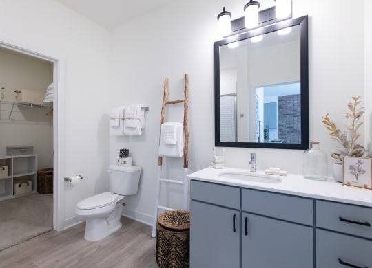 a bathroom with gray cabinets and white walls