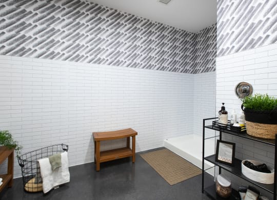 a bathroom with white brick walls and a black shelving unit with a wooden bench and a