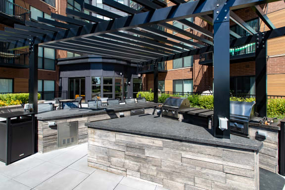 an outdoor patio with a grill and lounge area