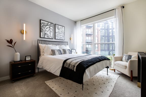 a bedroom with a large window and a large bed with a black and white comforter