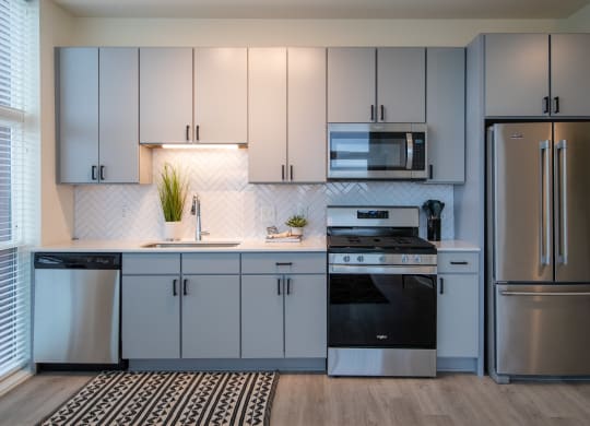 a kitchen with gray cabinets and a black and white rug